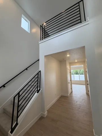 Open-concept entry featuring wood-finish flooring, recessed lighting, and a contemporary black horizontal bar railing