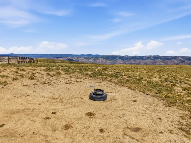 Expansive terrain with distant mountain ranges and a rustic wood fence line