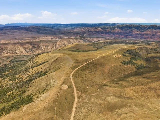 Expansive terrain featuring varied topography, distant mountain ranges, and scattered evergreen trees