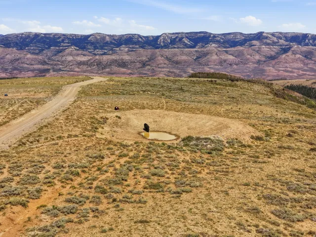 Dirt road, excavated pond, and arid landscape with distant mountains