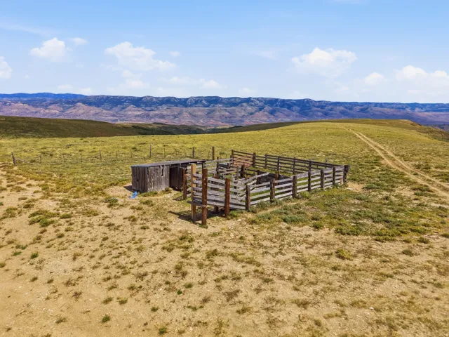 Wooden corral with an adjacent shed structure, set within a vast open landscape
