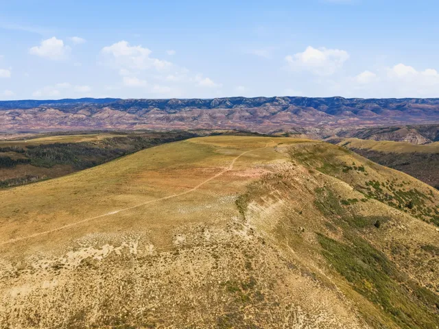 Expansive land with varied topography, including rolling hills and distant mountainous terrain