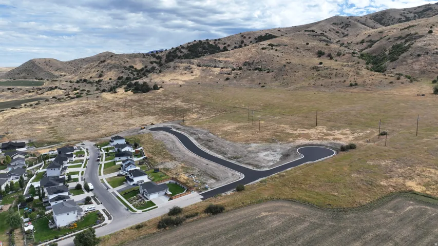 Established residential development with paved streets, surrounded by expansive natural terrain, and distant mountain backdrops