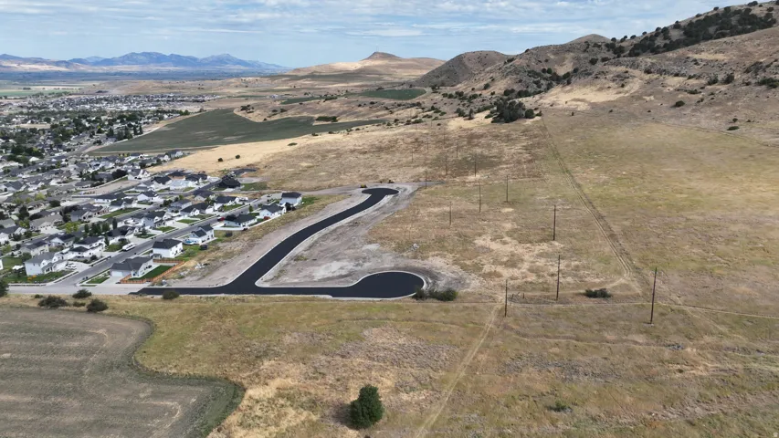 Newly paved cul-de-sac with surrounding residential development and distant mountainous terrain