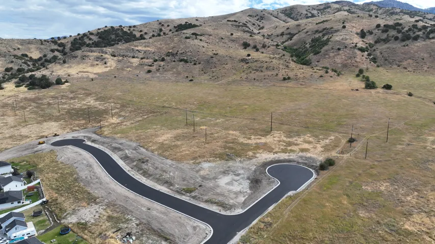 Newly paved cul-de-sac with surrounding undeveloped land and mountainous terrain