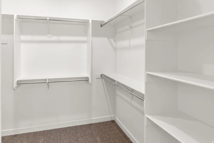 Walk-in closet with multiple hanging rods and extensive built-in shelving