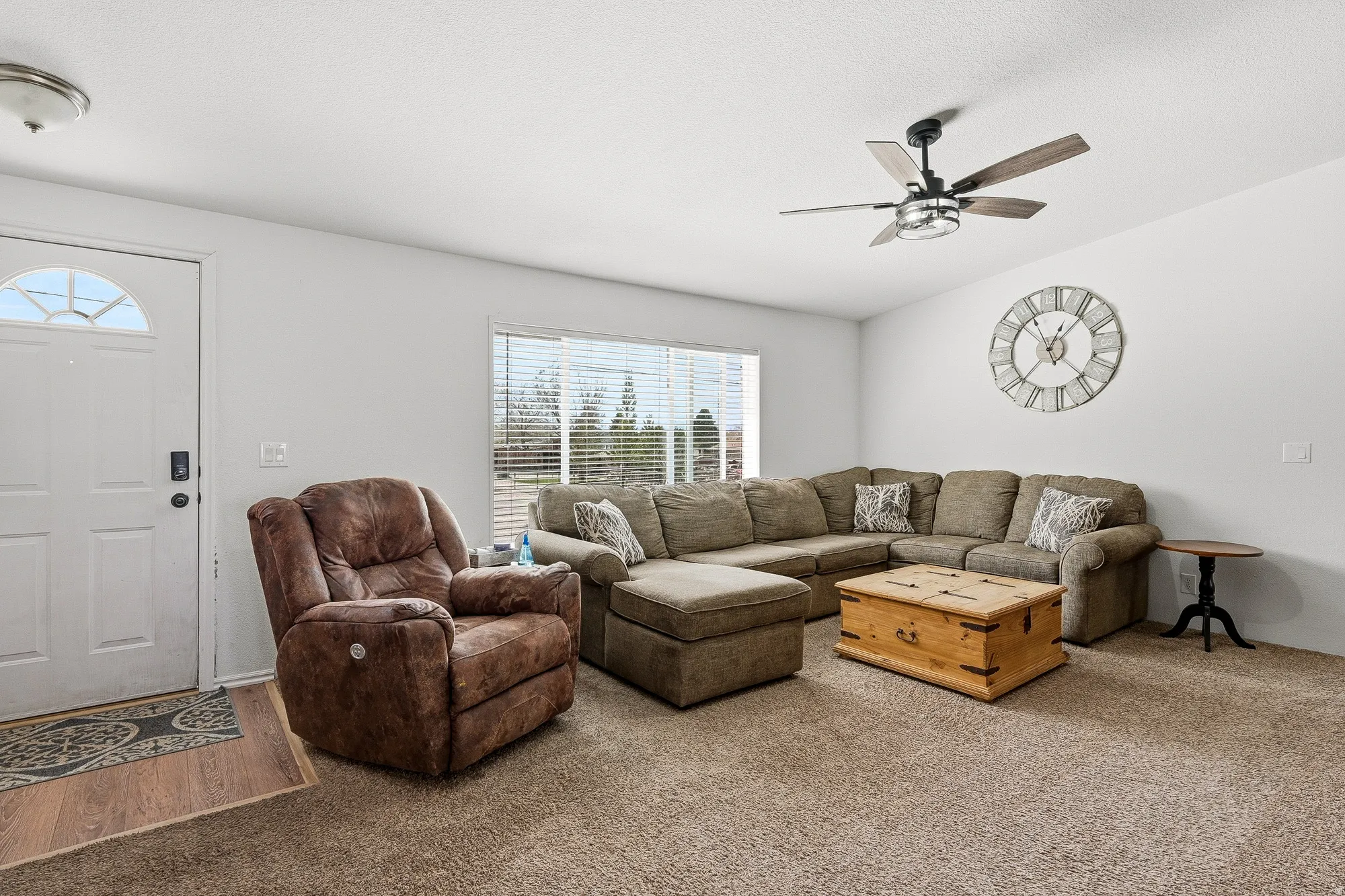 White entry door with an arched window, wood-finish flooring, and a ceiling fan with integrated lighting