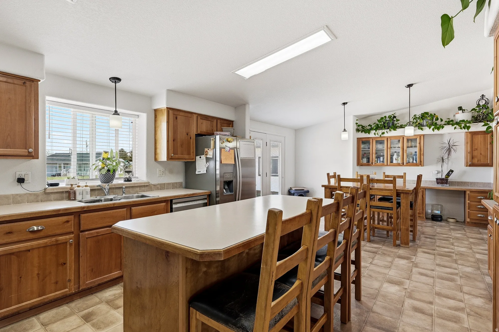 Kitchen featuring wood cabinetry, stainless steel appliances, a center island with seating, and tile flooring
