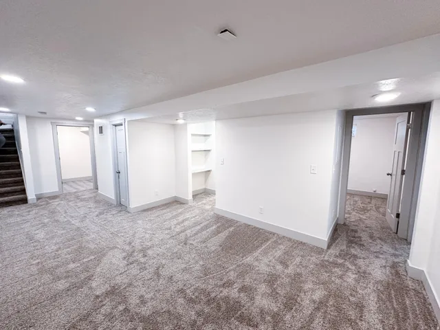 White walls, recessed lighting, built-in shelving, gray trim, and gray patterned carpet