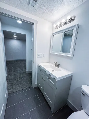 Bathroom featuring a single vanity with a white countertop and a framed mirror