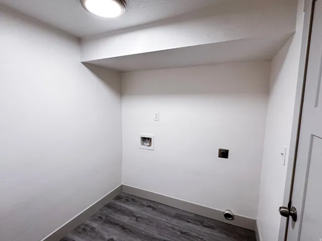 Utility area featuring wood-finish flooring, white walls, and a flush-mount ceiling light