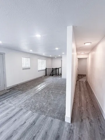 Recessed ceiling lighting, wood-finish flooring, two windows, wall-to-wall carpeting, and a black metal railing