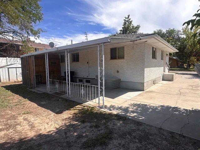 White brick exterior with covered patio, concrete steps, and paved driveway