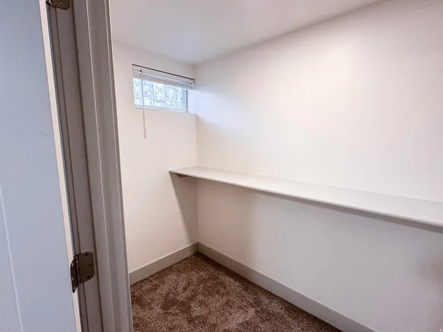 Built-in shelving, white walls, and a window with blinds