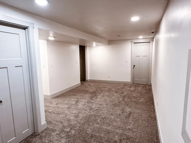 Neutral-toned carpeting, white walls, recessed lighting, and white trim