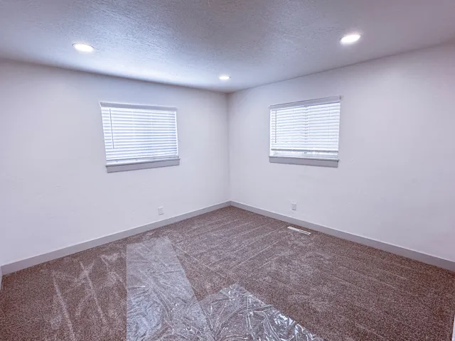 Recessed ceiling lighting, two windows with blinds, and neutral-toned wall-to-wall carpeting