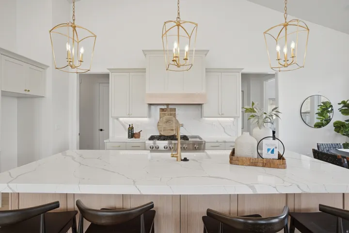 Kitchen island with a light-toned countertop, wood-finish paneling, and three pendant light fixtures