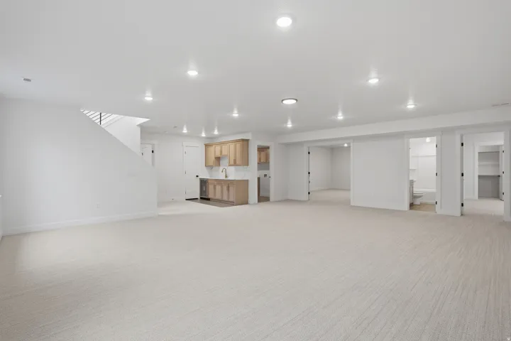 Spacious open-concept area featuring recessed lighting, a built-in wet bar with wood-finish cabinetry, and neutral carpeting