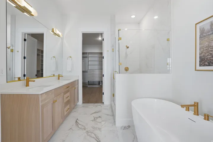 Dual vanity with light wood-finish cabinetry, white countertop, and gold-finish fixtures
