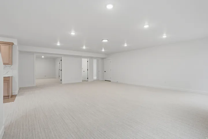 Expansive room featuring recessed lighting, light-toned carpet, and a built-in cabinetry unit with a countertop and backsplash