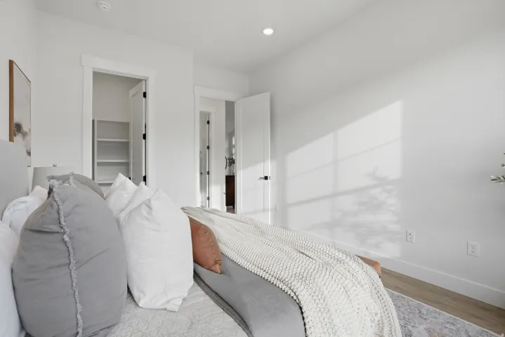 Recessed lighting, white walls, wood-finish flooring, white trim, and a built-in closet with shelving