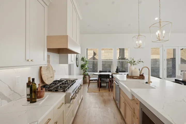 Spacious kitchen featuring an expansive island, white cabinetry, integrated range with custom wood hood, and white countertops