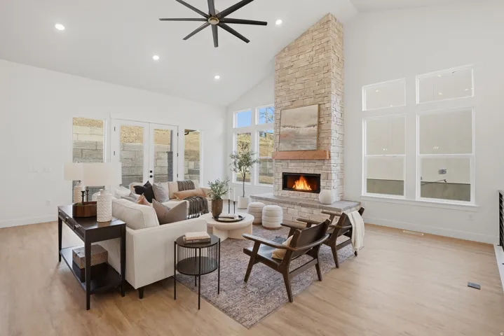 Vaulted ceilings with recessed lighting, a stone-clad fireplace with a wood mantle, and wood-finish flooring