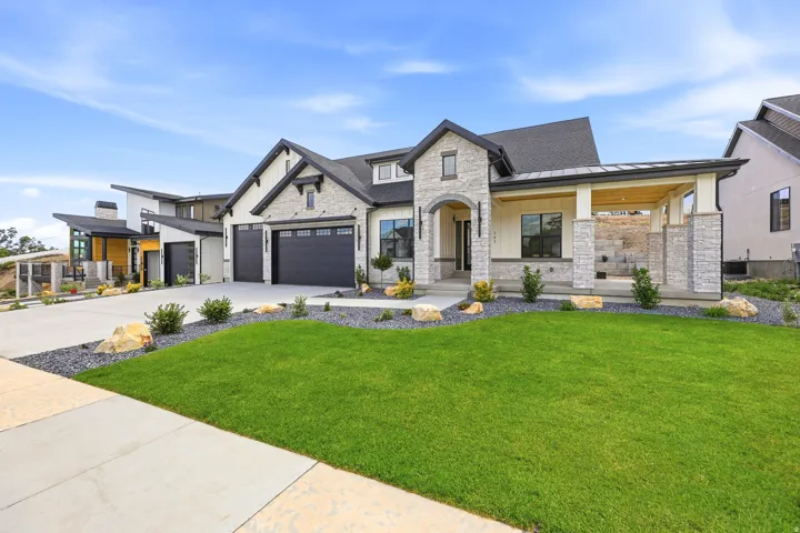 Stone and siding exterior with dark trim accents, a concrete driveway, an arched entry, and an attached covered patio