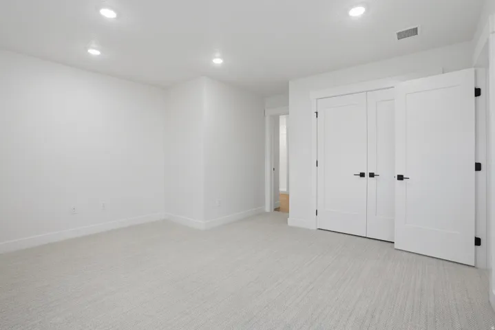 Recessed ceiling lighting, light-toned carpeting, white walls, and white doors with matte black hardware
