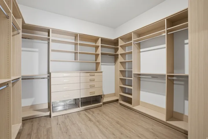 Custom closet system featuring light wood-finish cabinetry, extensive shelving, integrated drawers, and chrome hanging rods