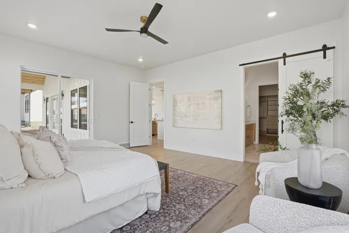 Spacious primary suite featuring hardwood flooring, recessed ceiling lighting, and a ceiling fan