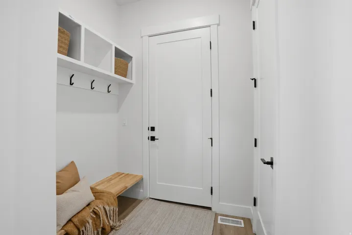 Built-in storage cubbies with hooks, solid-core doors with black hardware, and wood-finish flooring