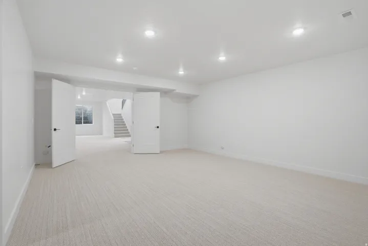 Spacious room featuring neutral carpeting, recessed lighting, and white walls