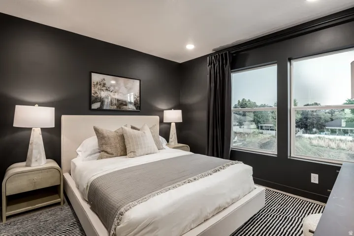 Recessed ceiling lighting, dark painted walls, large windows, and a carpeted floor