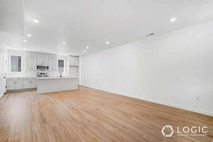 Open-concept living space featuring wood-finish flooring, recessed lighting, and a kitchen with light-toned cabinetry