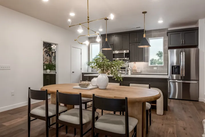 Open-concept dining area with wood-finish flooring, recessed lighting, and a linear chandelier