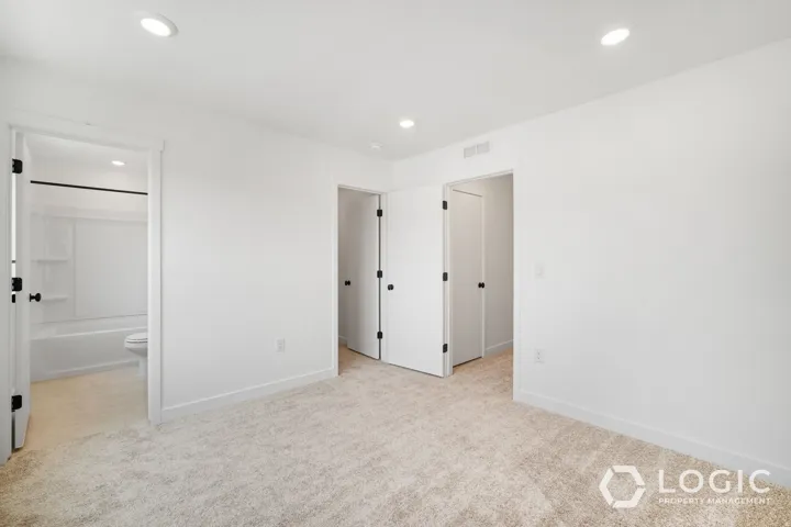 Plush carpet flooring, recessed ceiling lighting, crisp white walls, and a white bathtub with a shower curtain rod