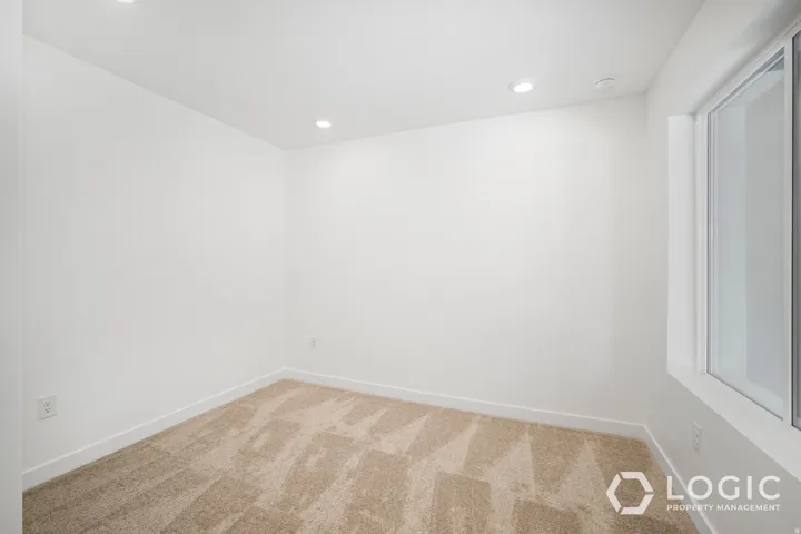 Bright, freshly finished interior space with clean white walls, recessed ceiling lighting, and geometric patterned carpet flooring throughout