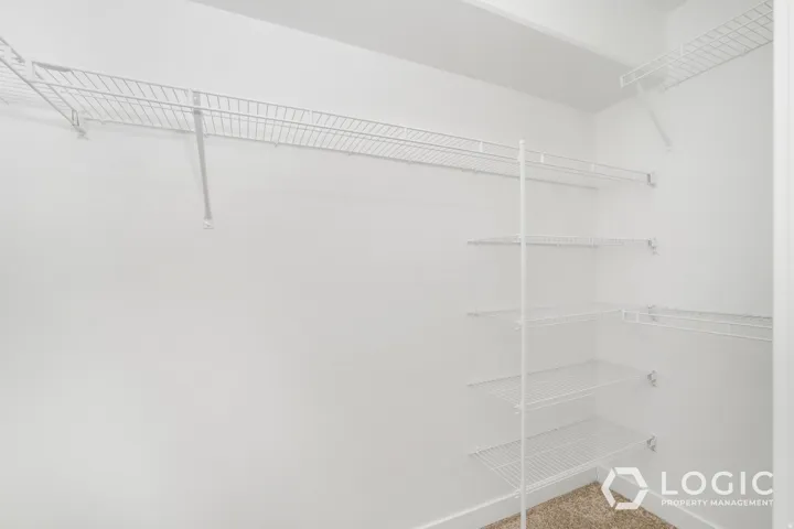 Walk-in closet with white wire shelving, white walls, and carpet flooring