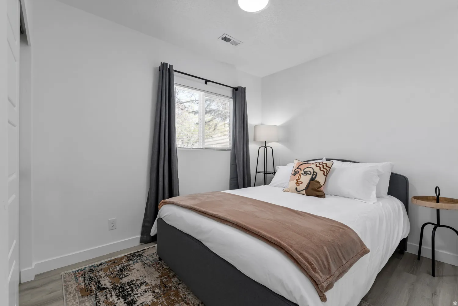 Unit #2Wood-finish flooring with white baseboards and a large window with curtain rod and drapes