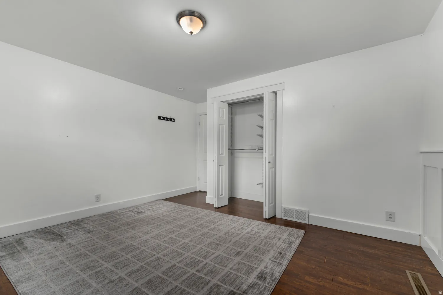 Wood-finish flooring, white walls, and a ceiling-mounted light fixture