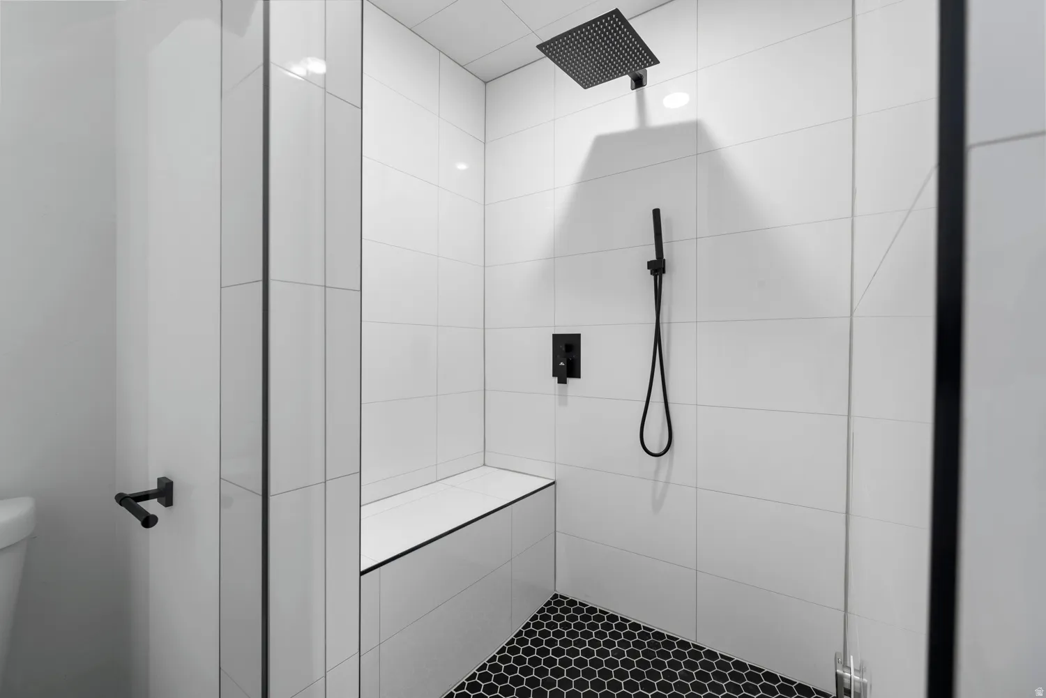 Unit #2 STEAM SHOWER! Walk-in shower with white subway tile, a built-in bench, matte black fixtures, and a black hexagonal tile floor