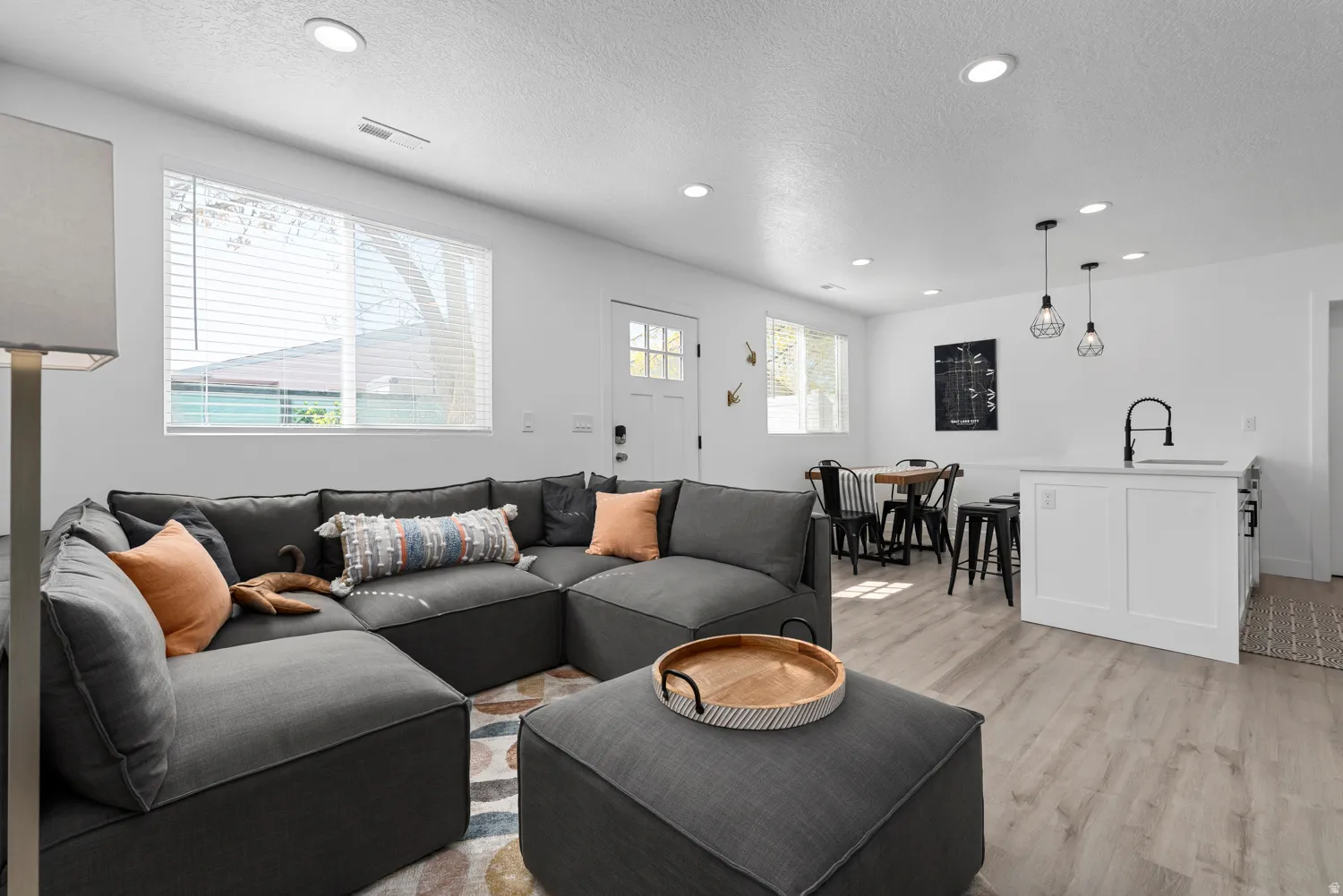 Unit #2Open-concept living area featuring a charcoal sectional sofa, wood-finish flooring throughout, and recessed ceiling lighting