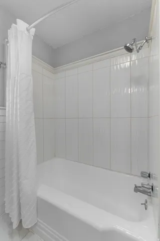White bathtub with chrome fixtures and white tiled surround
