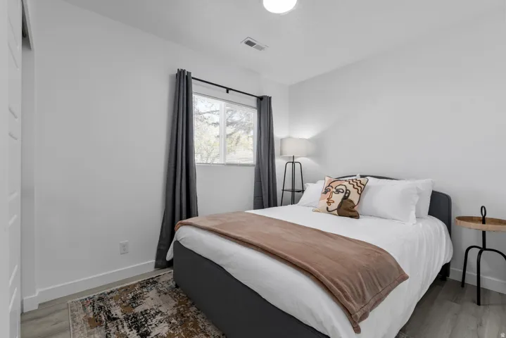 Unit #2Wood-finish flooring with white baseboards and a large window with curtain rod and drapes