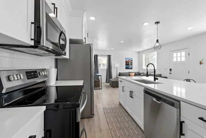 Unit #2Stainless steel appliances, white cabinetry with black hardware, white countertops, wood-finish flooring, and recessed lighting
