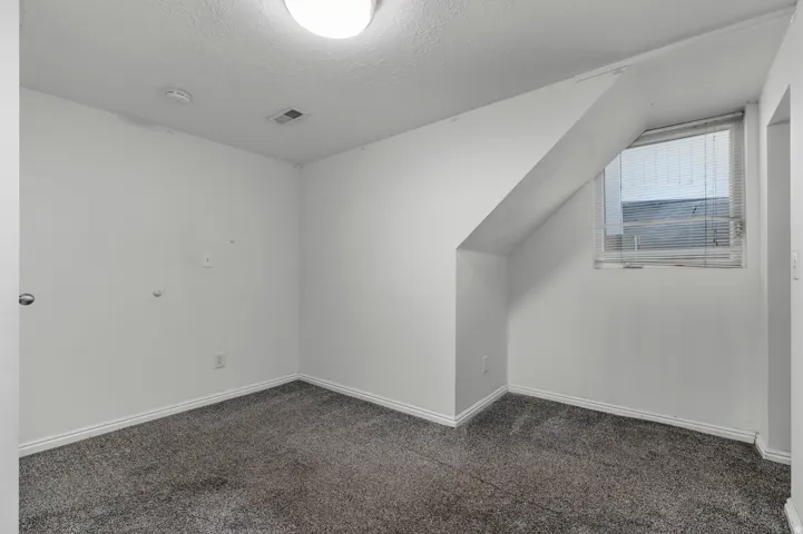 Carpeted flooring with white baseboards, a single window with blinds, and a flush mount ceiling light fixture