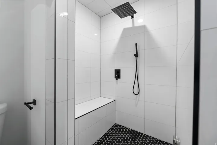 Unit #2 STEAM SHOWER! Walk-in shower with white subway tile, a built-in bench, matte black fixtures, and a black hexagonal tile floor