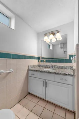 White vanity with a light-toned granite countertop, undermount sink, and chrome faucet