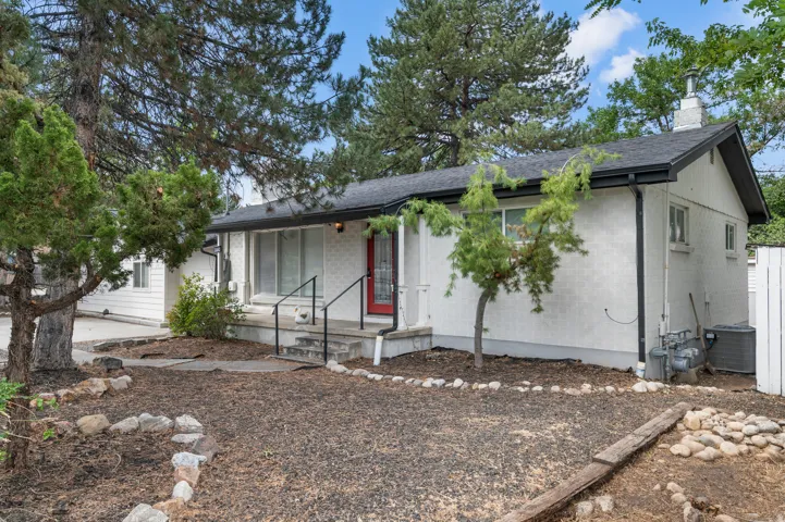 White stucco exterior with black trim, a red front door, and a concrete porch with black railings